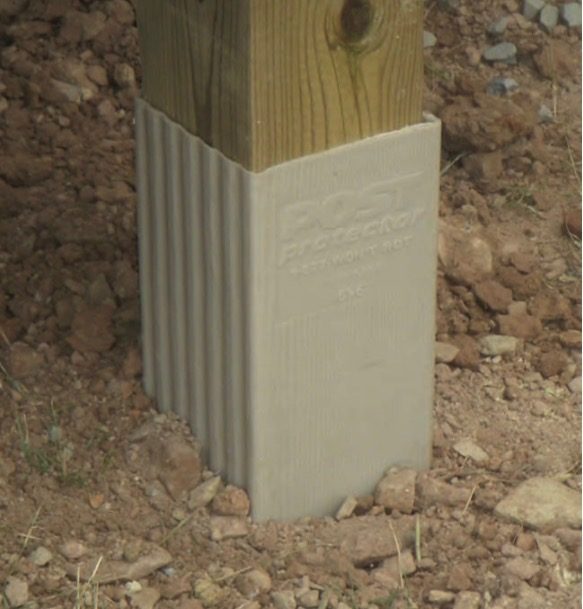 Post protector sleeve on a treated post set in the ground